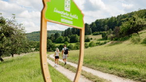 Vorschaubild: Zwei Personen wandern hinter Aussichtsrahmen, Link zum Pressebild in hoher Auflösung