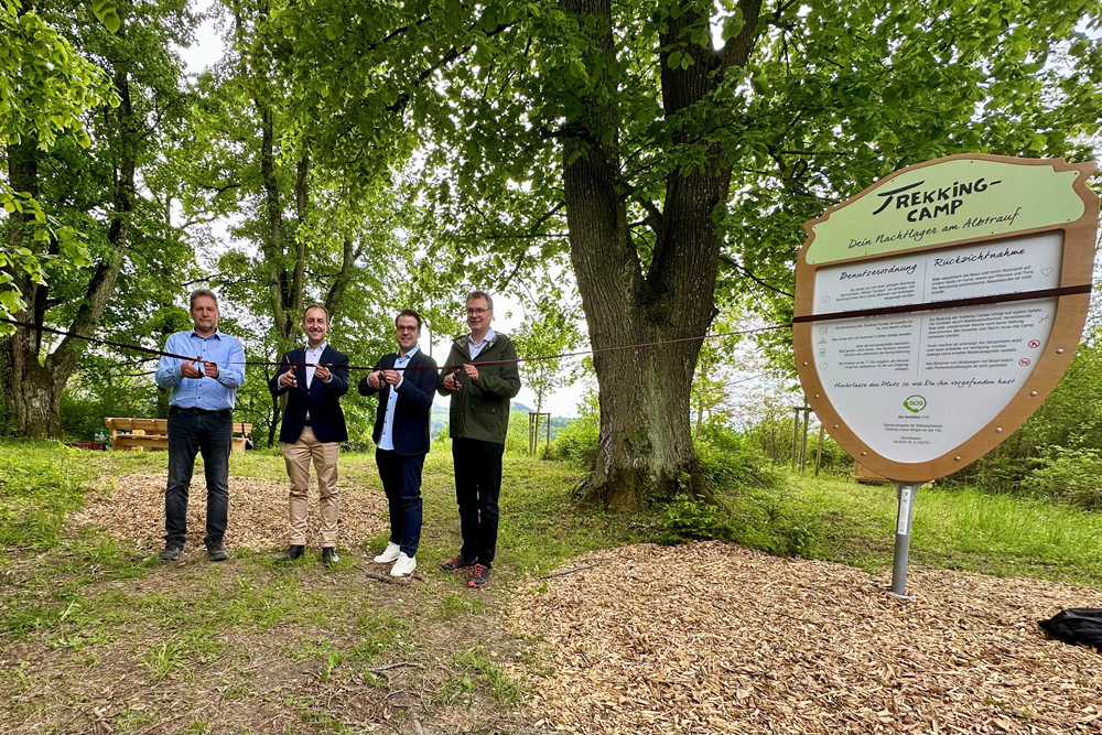 Vier Männer mit Schere schneiden ein Band durch, welches sich in einem Wald befindet. 